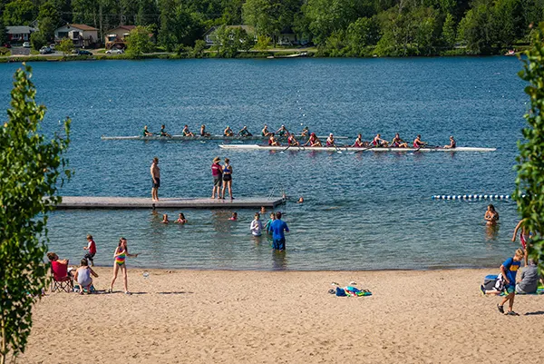 Rowers on the water and swimmers at the beach at Garrow Park.