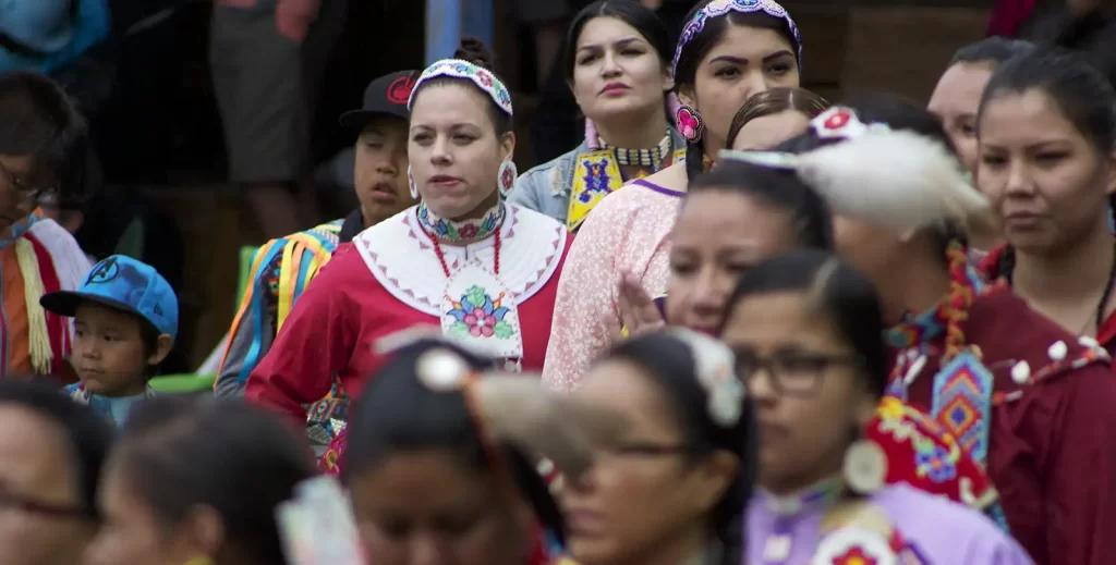 A crowd of women during a powwow in traditional ceremonial dress.