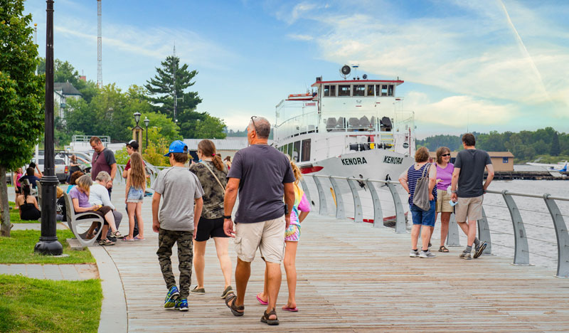 Visitors walk along the boardwalk on Kenora's Lake of the Woods harbourfront.